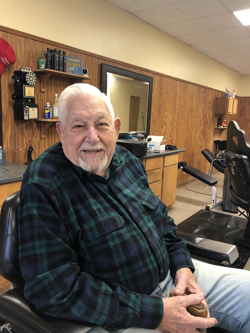 A smiling gentleman in a flannel shirt inside Pete's Barber Shop